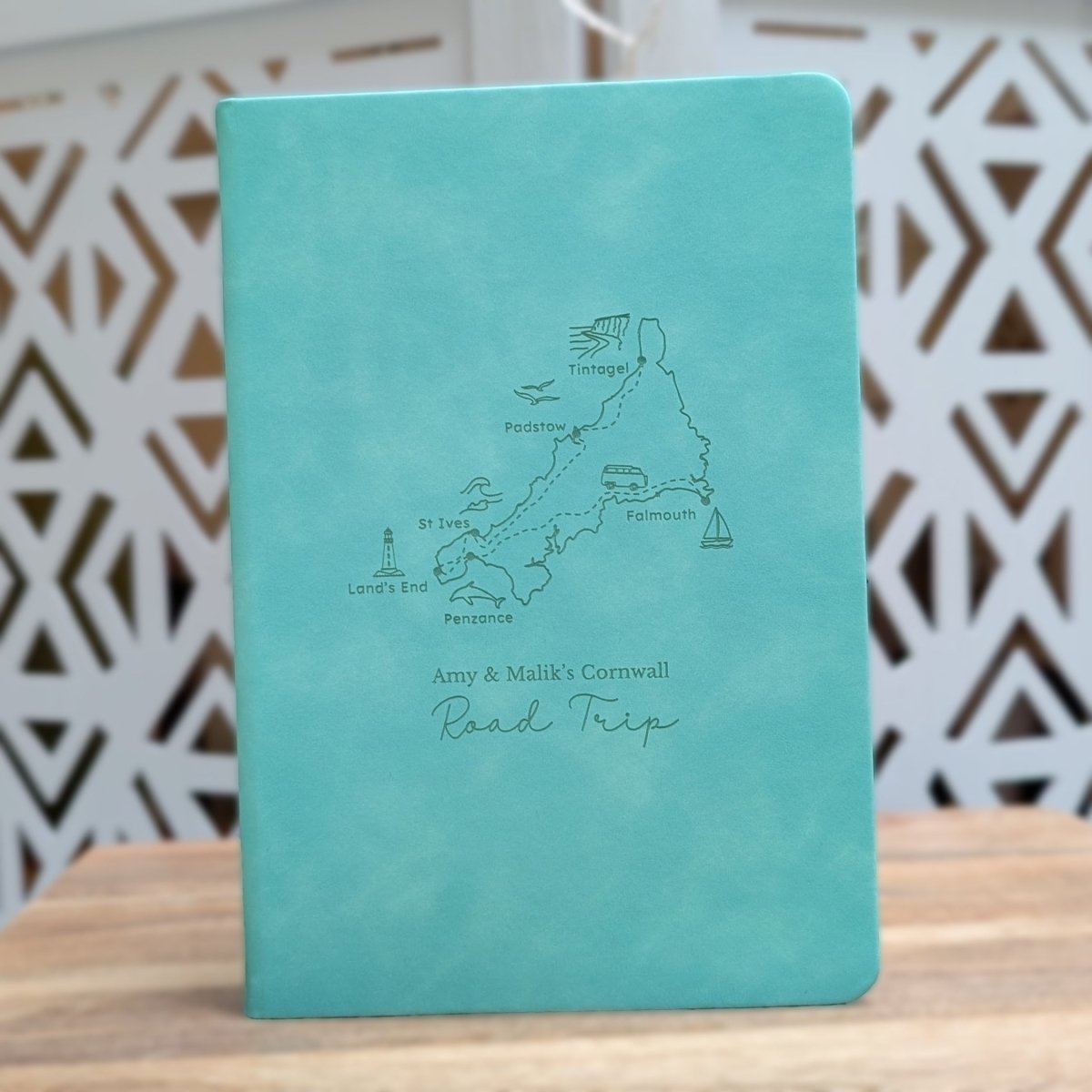 Turquoise engraved Cornwall road trip journal featuring six destinations, a campervan, coastal illustrations and personalised cover wording.