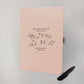 Blush pink personalised Route 66 road trip journal with black route artwork, American landmarks, convertible car and matching pen.