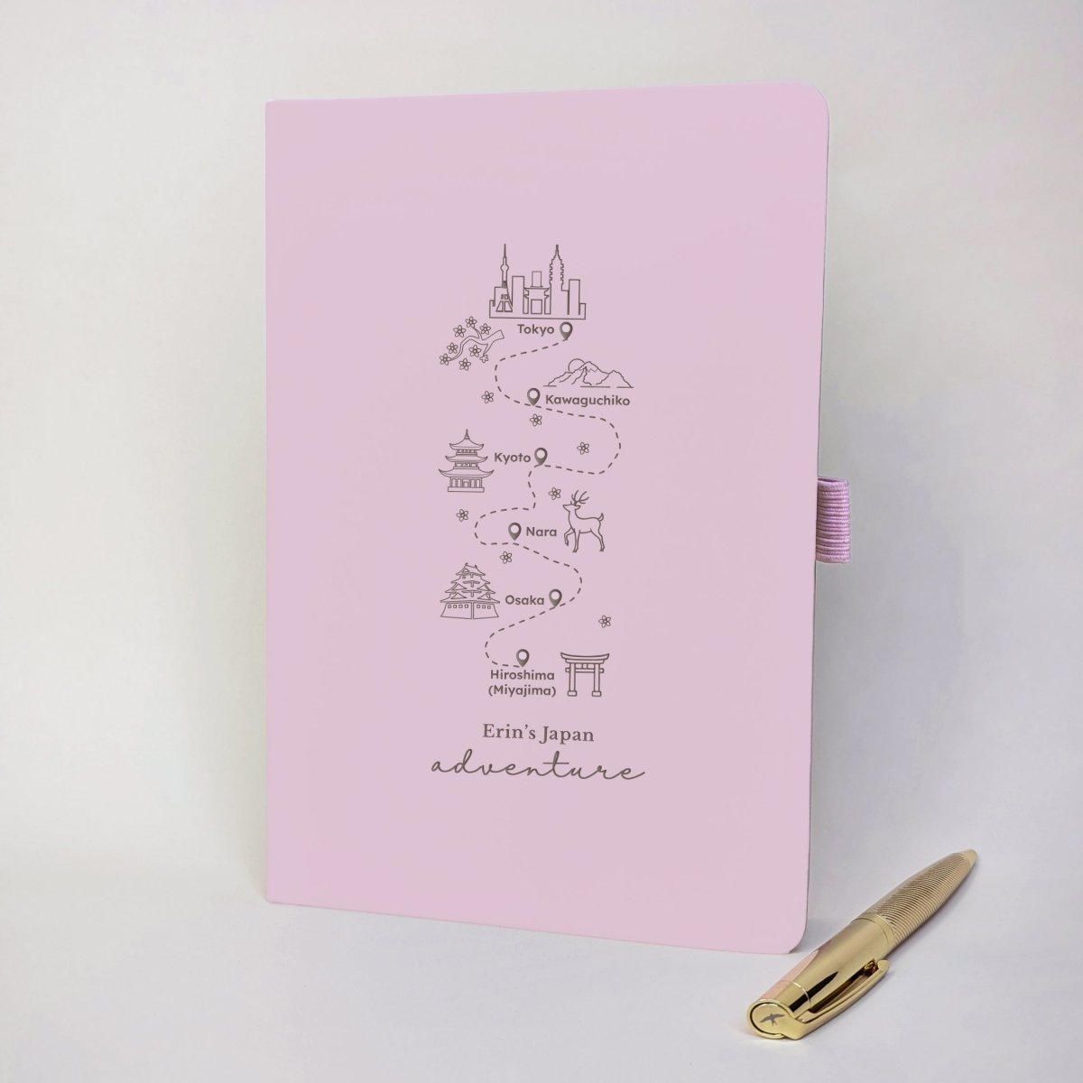 Pink personalised Japan travel journal featuring six destinations, cherry blossoms, Mount Fuji, traditional landmarks and a matching gold pen.