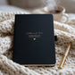 Personalised black “Letters to Dad” grief journal with gold remembrance wording, styled on a soft chunky knit blanket with a gold pen and warm drink nearby.
