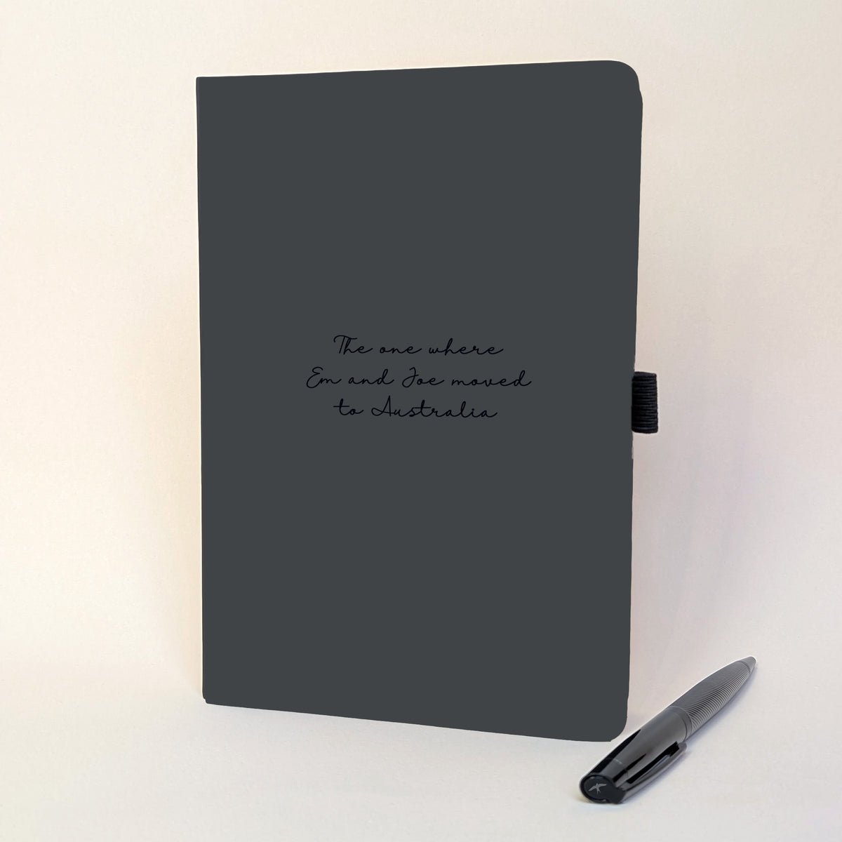 Personalised black journal and black pen with handwritten-style text reading “The one where Em and Joe moved to Australia”, a thoughtful emigrating or moving abroad gift.