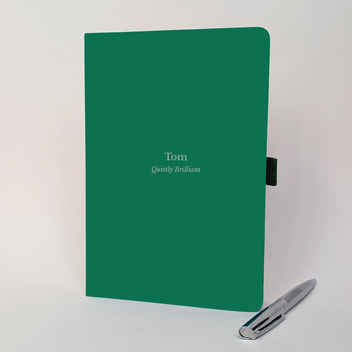 Green personalised employee appreciation journal for Tom reading “Quietly Brilliant”, shown with a silver pen.