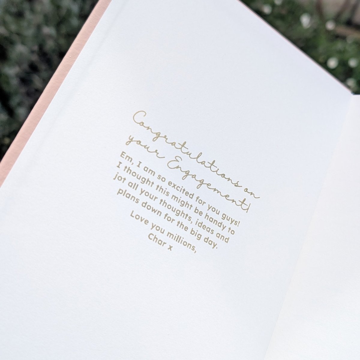 Open personalised engagement journal showing a gold inside-cover congratulations message, demonstrating the optional personal message that can be added for the newly engaged couple.
