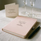 Blush personalised engagement journal with black pen styled on a table with champagne flutes and an engagement card.
