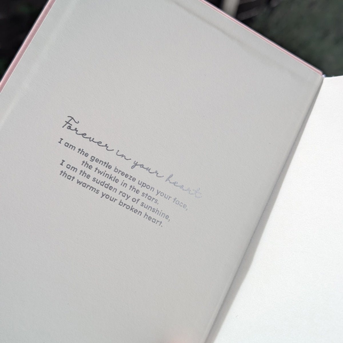 An open grief journal showing  a printed sentimental grief poem in silver script and sans serif text, photographed close up.