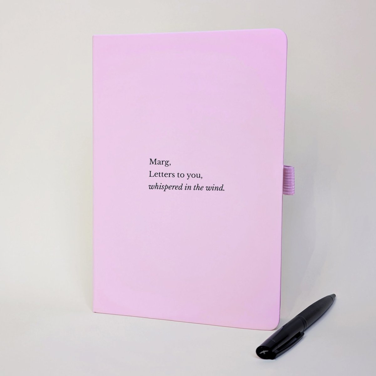 Personalised pink grief journal reading “Marg, Letters to you, whispered in the wind” with black pen.
