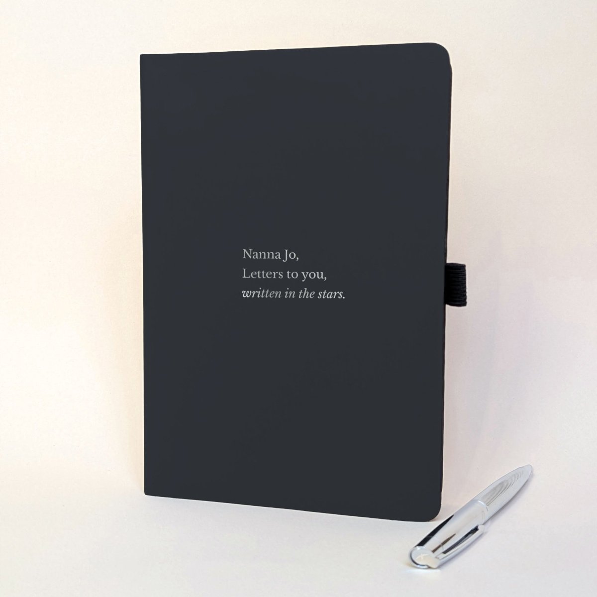 Personalised black grief journal reading “Nanna Jo, Letters to you, written in the stars” with silver pen.