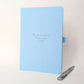 Light blue personalised keepsake journal with silver pen, featuring “The one where Lisa says I do”, an example of custom wording for a wedding, engagement or special life milestone gift.